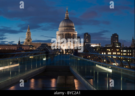 Der Dome Saint Paul's Cathedral am Ufer der Themse in London mit der Millennium Bridge im Vordergrund, beleuchtet in der Dämmerung. Stockfoto