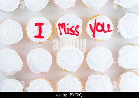 Reihen von Cupcakes mit roten Buchstaben "Ich vermisse dich" geschrieben auf weißem Zuckerguss Stockfoto