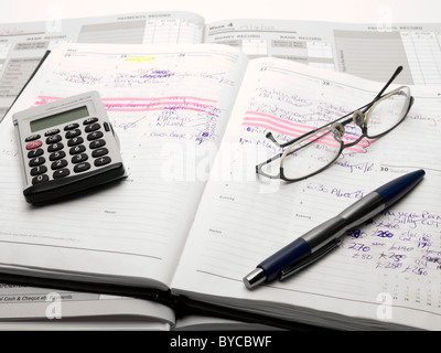 Taschenrechner, Lesebrille und einem Stift auf ein Tagebuch und Konten Buch Stockfoto