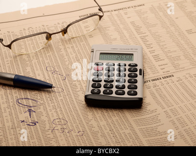 Taschenrechner, Kugelschreiber und lesen Gläser auf einer Finanzzeitung Stockfoto