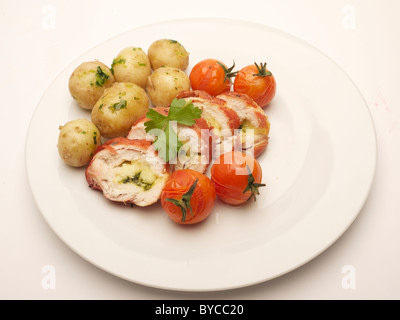 Gekochte Mahlzeit auf einem Teller, einschließlich Huhn, Kartoffeln und Tomaten Stockfoto