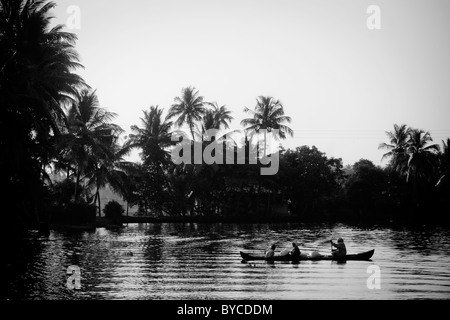 Menschen in einem traditionellen hölzernen Kanu überqueren einen Kanal in den "Backwaters" in der Nähe von Alappuzha (aka Alleppey) in Kerala, Indien. Stockfoto