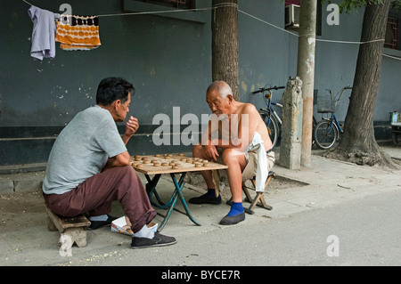 Alte Männer spielen Xiangqi oder chinesisches Schach in Hutong District von Peking, China Stockfoto