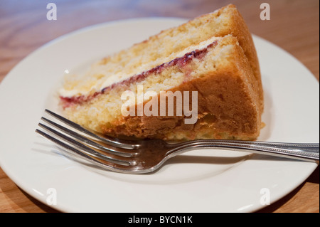 Eine Scheibe von Victoria Biskuit mit einer Gabel auf einem weißen Teller. Stockfoto