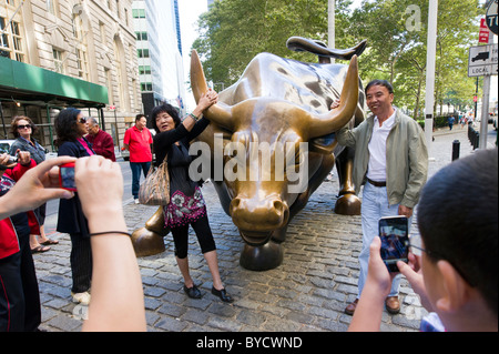 Touristen posieren für Fotos neben der Ladestation Stier Skulptur in der Nähe von Wall Street, New York City, America, USA Stockfoto