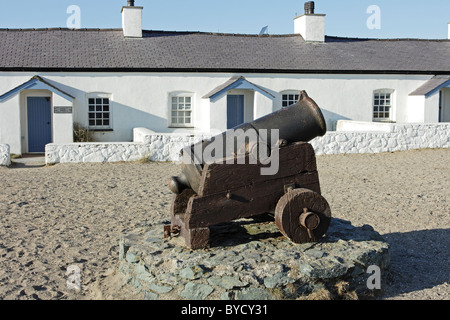 Eine Reihe von stillgelegten Piloten Hütten auf Llanddwyn Island, Anglesey, mit einem kastanienbraunen Kanon im Vordergrund Stockfoto
