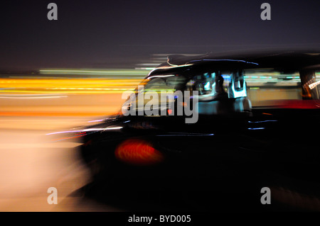 Black Taxi Cab Umzug durch die Straßen von London in der Nacht mit Motion blur Stockfoto