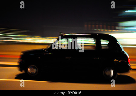 Black Taxi Cab Umzug durch die Straßen von London in der Nacht mit Motion blur Stockfoto