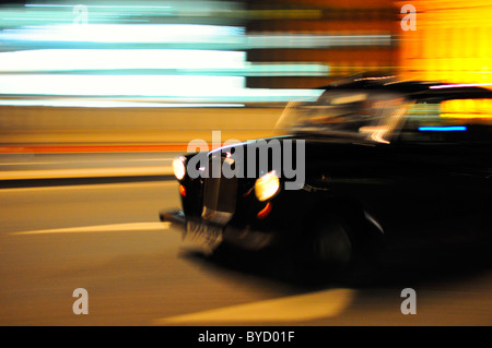 Black Taxi Cab Umzug durch die Straßen von London in der Nacht mit Motion blur Stockfoto