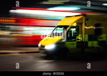 Krankenwagen rauschenden Vergangenheit ein roten Bus mit Motion blur Stockfoto