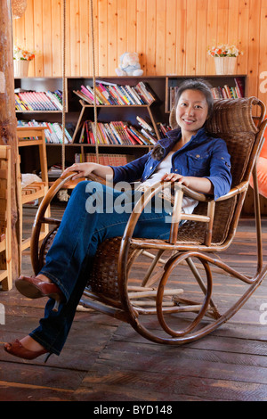 Schöne junge Chinesin Entspannung in Bambus Spazierstock Schaukelstuhl in Lijiang, Yunnan Provinz, China. JMH4845 Stockfoto