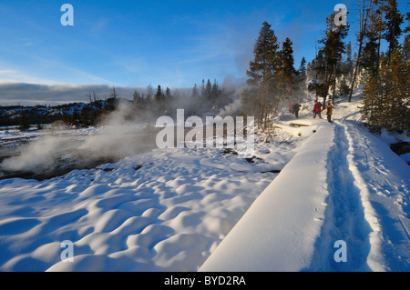 Besucher gehen durch tief verschneite Trail in der Nähe von einer heißen Quelle. Norris Geyser Basin, Yellowstone-Nationalpark, Wyoming, USA. Stockfoto