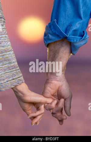 Älteres Paar Hand in Hand bei Sonnenuntergang in Nahaufnahme Stockfoto