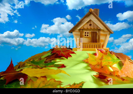 Holzhaus auf einem Hügel bedeckt mit gefallene Herbstlaub unter blauen Wolkenhimmel Stockfoto