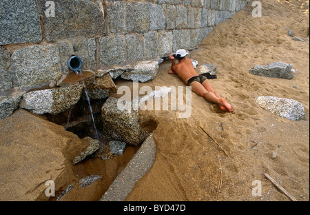 Neben einem Strand Badenden strömt Wasser aus ein Ablaufrohr an einem touristischen Strand am Cheoc Van Strand Coloane Insel, Macau, China. Stockfoto