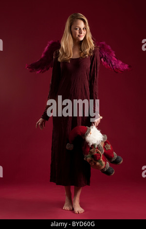 Blond rot gekleidete Engel mit Santa Claus Puppe Stockfoto