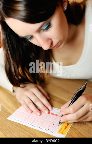 Junge Frau, die einen Lottoschein ausfüllen Stockfoto