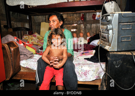 43, Mutter und Tochter, 8, sitzt auf einem Bett in ihrer bescheidenen Hütte in einer Favela oder Shanty Town, das Familienleben durch das sammeln, Stockfoto