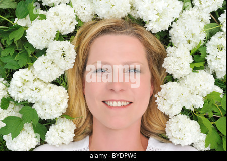 Junge Frau, die Verlegung in Blumen - Schneebälle Stockfoto