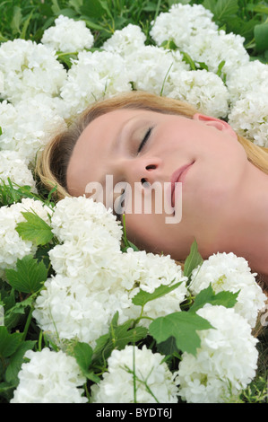 Junge Frau, die Verlegung in Blumen - Schneebälle Stockfoto