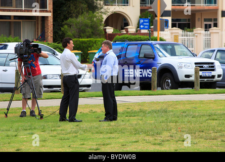 Kanal 9 News Interview mit dem 9News Auto im Hintergrund gefilmt. Stockfoto