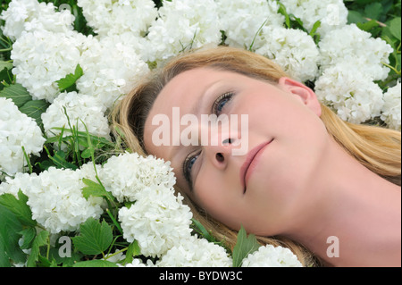 Junge Frau, die Verlegung in Blumen - Schneebälle Stockfoto