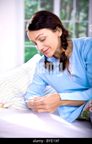 Frau mit Handy im Bett Stockfoto