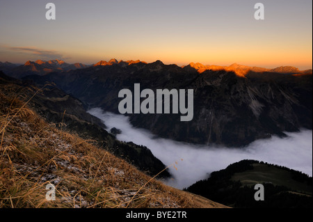 Bergtal unter Nebel mit Berggipfeln morgens Licht, Allgäuer Alpen, Kleinwalsertal Tal, Vorarlberg, Österreich Stockfoto