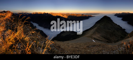 Bergtal unter Nebel mit Berggipfeln morgens Licht, Allgäuer Alpen, Kleinwalsertal Tal, Vorarlberg, Österreich Stockfoto