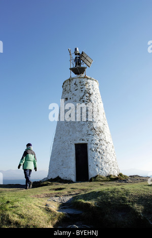 Ein Spaziergänger nähert sich den alten Leuchtturm auf Llanddwyn Island, Anglesey, Nordwales Stockfoto