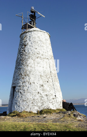 Ein Besucher ruht in der Sonne unter dem alten Leuchtturm auf Llanddwyn Island in Anglesey, die jetzt solarbetrieben Stockfoto