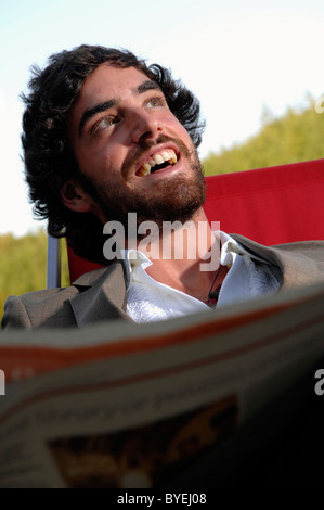 Ein glücklich junger Mann immer am Lächeln und Lachen lesen Papier Stockfoto