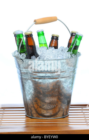 Bier Eimer gefüllt mit verschiedenen Flaschen und Eiswürfel auf Teak Tisch vor einem weißen Hintergrund. Stockfoto