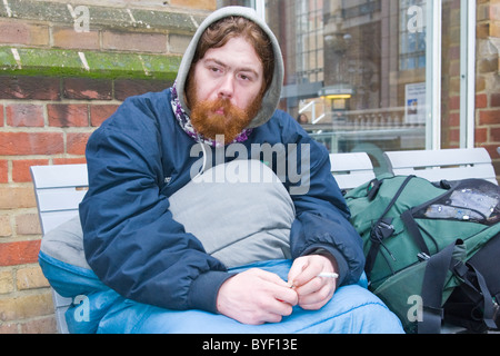 London, Liverpool Street Station, rote Leitung & bärtigen jungen Obdachlosen Mann eingewickelt im Schlafsack Rauchen - redundante 2 Jahre Stockfoto