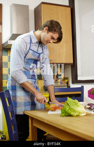 kaukasischen erwachsenen Mannes Schneiden von Gemüse in der Küche. Vertikale Form, Seitenansicht Stockfoto