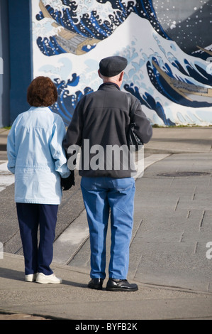 Ein älteres paar Erwachsene wartet an einer Kreuzung vor dem Überqueren der Straße in der Innenstadt von Olympia, Washington. Stockfoto