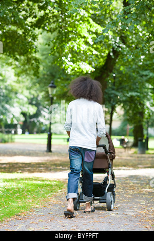 Rückansicht des jungen Mannes schieben Kinderwagen im park Stockfoto