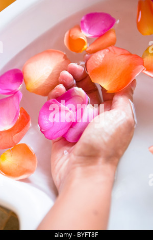 Nahaufnahme von Hand in Spa Schüssel mit Wasser und Rosenblättern Stockfoto