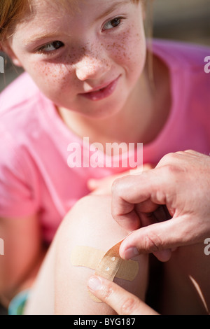 Vater seine Töchter Knie Pflaster aufkleben Stockfoto