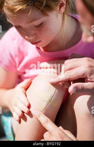 Vater seine Töchter Knie Pflaster aufkleben Stockfoto