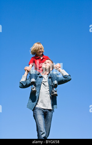 Vater Piggy Backing Tochter gegen klaren Himmel Stockfoto