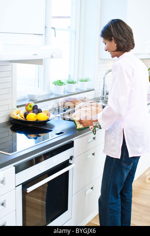 Frau mit Brot auf Tablett in Küche Stockfoto