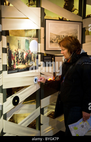 Touristen tragen "Stethoskop" Kopfhörer / Kopfhörer audio-Guide mit Blick auf eine Anzeige. Florence Nightingale Museum. London. VEREINIGTES KÖNIGREICH. Stockfoto