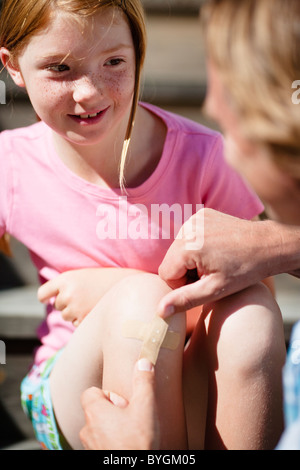 Vater seine Töchter Knie Pflaster aufkleben Stockfoto