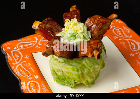 Essen - Baby Back Ribs in einen Baby-Kopf Eisbergsalat. Stockfoto