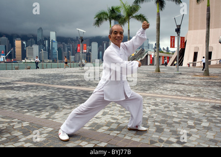 Porträt von Tai Chi Meister Herr Ng an eine Schatten-Boxen-Haltung schießen Sie auf die Avenue of Stars mit Hong Kong Wolkenkratzern Stockfoto