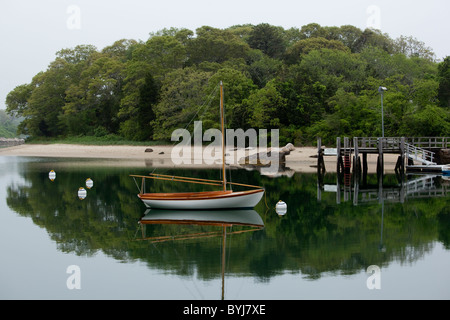 USA, Massachusetts, Woods Hole, kleines Segelboot spiegelt sich in den stillen Wassern der geschützten Bucht an nebligen Sommerabend Stockfoto