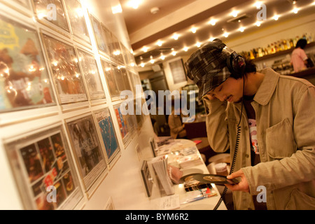 Anhören von Musik-CD auf einem Horchposten, 'Zeichen Sie' Café/Bar in Aoyama, Tokio, Japan, Oktober 2003. Stockfoto