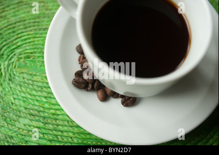 Tasse Kaffee auf grüner Bast-Matte mit lokalen frisch verarbeiteten Kaffeebohnen auf der Seite. Honduras, Mittelamerika. Stockfoto