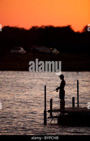 USA, Texas, Lake Arrowhead State Park, junger Mann halten Angelrute beim Angeln aus Frischwasser dock bei Sonnenuntergang am Sommerabend Stockfoto